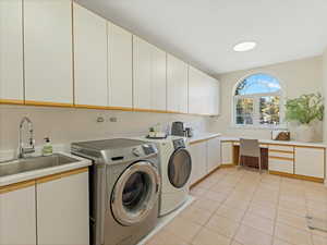Washroom with light tile patterned floors, separate washer and dryer, cabinet space, and a desk