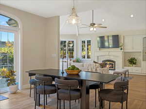 Dining area with light wood-style flooring, a glass covered fireplace, a ceiling fan, and recessed lighting