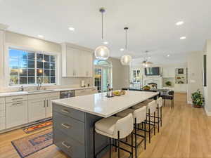 Kitchen with white cabinetry, light wood-style floors, a fireplace, a kitchen bar, and recessed lighting