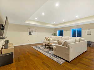 Living area featuring recessed lighting, dark wood finished floors, and a tray ceiling