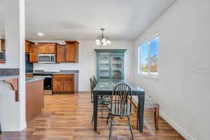 Kitchen featuring brown cabinets, appliances with stainless steel finishes, light wood-type flooring, a chandelier, and recessed lighting