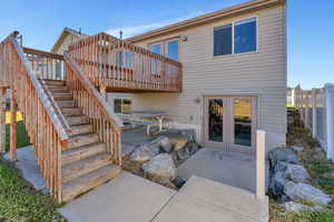 Back of house featuring stairs, a wooden deck, a patio area, and french doors