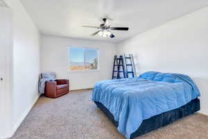 Carpeted bedroom with a ceiling fan and baseboards