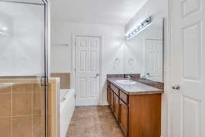 Full bathroom featuring a garden tub, a stall shower, vanity, and light tile patterned floors