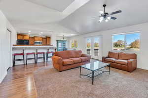 Living room with lofted ceiling, a ceiling fan, light wood-style floors, and recessed lighting