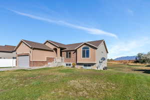 View of front of home featuring a front yard, concrete driveway, an attached garage, and brick siding