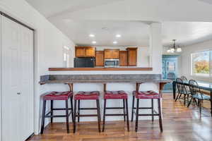 Kitchen featuring brown cabinetry, recessed lighting, light wood-type flooring, plenty of natural light, and dark countertops
