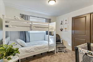 Carpeted bedroom with a closet and a textured ceiling