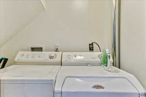 Laundry area featuring washing machine and clothes dryer, a textured ceiling, and vaulted ceiling