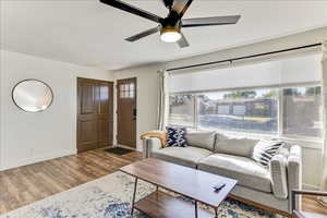 Living area with wood finished floors, plenty of natural light, and a ceiling fan