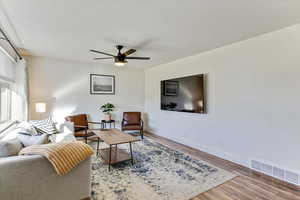 Living area featuring light wood-type flooring, ceiling fan, and a textured ceiling