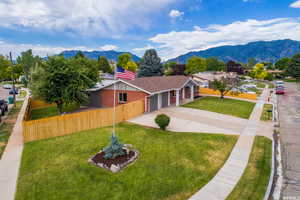 View of front of home featuring driveway, a mountain view, brick siding, a porch, and an attached garage