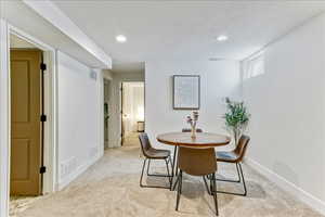 Dining room with light colored carpet, a textured ceiling, and recessed lighting