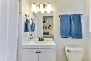 Ensuite bathroom with a shower with curtain, vanity, and a ceiling fan