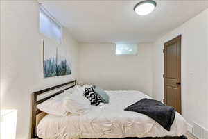 Bedroom featuring a textured ceiling, multiple windows, and a textured wall