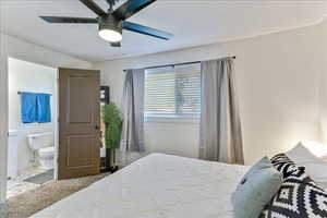 Carpeted bedroom featuring ceiling fan and ensuite bathroom