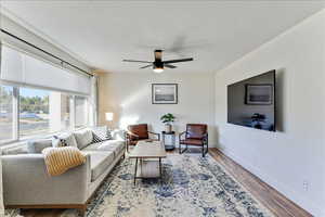 Living room featuring light wood-style floors, ceiling fan, and a textured ceiling