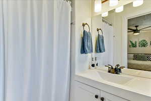 Ensuite bathroom featuring a shower with shower curtain, vanity, and ceiling fan