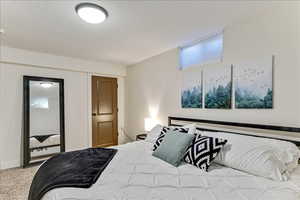 Bedroom with a textured ceiling and light carpet