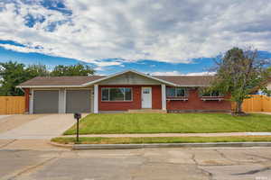 Ranch-style home featuring brick siding, driveway, a shingled roof, and a garage