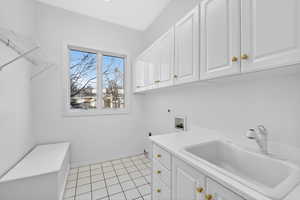Washroom featuring washer hookup, light tile patterned floors, electric dryer hookup, and cabinet space