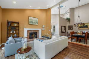 Living area with ceiling fan, wood finished floors, a fireplace, high vaulted ceiling, and recessed lighting