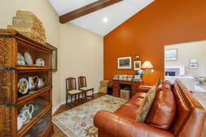 Living room featuring a tile fireplace, beam ceiling, wood finished floors, high vaulted ceiling, and recessed lighting