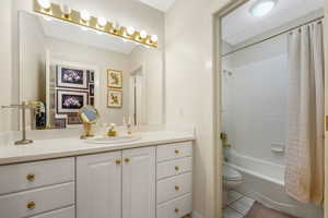 Bathroom featuring vanity, shower / bath combination with curtain, and light tile patterned floors