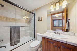 Full bathroom featuring ensuite bath, vanity, and enclosed tub / shower combo