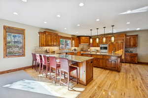 Kitchen with brown cabinets, a breakfast bar, light stone counters, and recessed lighting