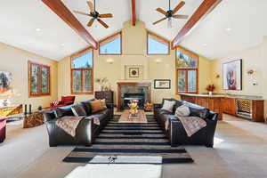 Living room with light colored carpet, high vaulted ceiling, wine cooler, beamed ceiling, and ceiling fan