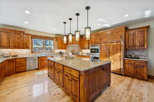 Kitchen with brown cabinets, light stone counters, tasteful backsplash, and recessed lighting
