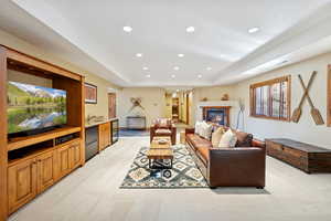 Living area with light carpet, recessed lighting, a tray ceiling, wine cooler, and a glass covered fireplace