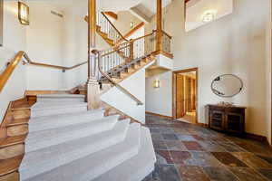 Staircase with a towering ceiling and stone finish flooring