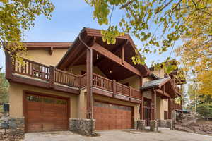 View of side of home featuring stone siding, stucco siding, an attached garage, and driveway