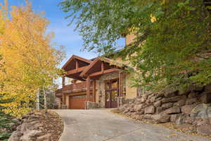 View of front facade with stone siding, concrete driveway, and an attached garage