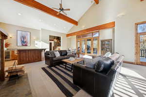 Living room with high vaulted ceiling, beamed ceiling, a ceiling fan, wine cooler, and dark colored carpet