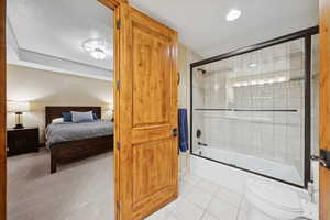 Bathroom with light tile patterned floors, shower / bath combination with glass door, ensuite bathroom, light colored carpet, and recessed lighting