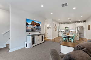 Living room featuring stairway, can lighting, light carpet, and an open floorplan