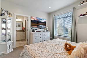 Primary bedroom featuring can lighting, carpet, a connected bathroom, and natural light