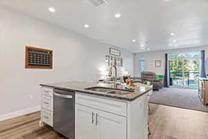 Kitchen with can lighting, white cabinetry, stainless steel appliances, an island with sink, and granite countertops