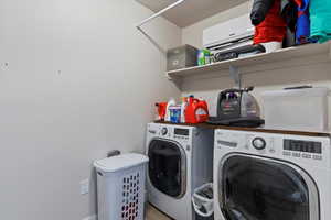 Laundry area featuring separate washer and dryer, an AC wall unit, a textured ceiling, and wood finished floors