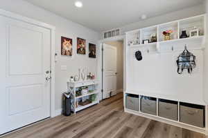 Mudroom featuring LVP floors, and built in shelving, access to laundry room