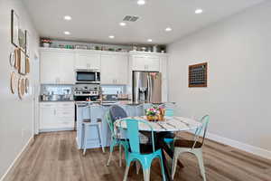 Kitchen with can lighting, white cabinetry, stainless steel appliances, an island with sink, and granite countertops