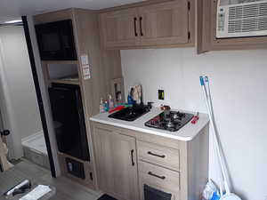 Kitchen featuring light countertops, black microwave, light brown cabinets, and gas stovetop