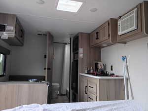 Kitchen with light countertops, a wall mounted AC, light brown cabinetry, and wood finished floors
