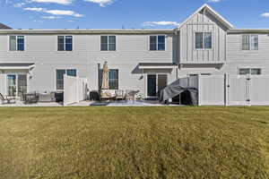 Back of house with board and batten siding, an outdoor living space, a patio, and a gate