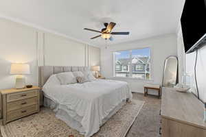 Bedroom featuring ornamental molding, ceiling fan, a textured ceiling, and light colored carpet