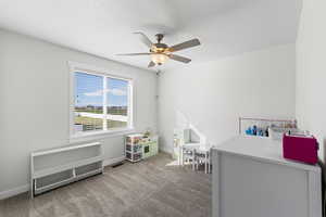 Bedroom with light carpet, ceiling fan, and a textured ceiling