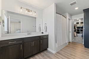Full bath with vanity, light wood-type flooring, a spacious closet, and recessed lighting